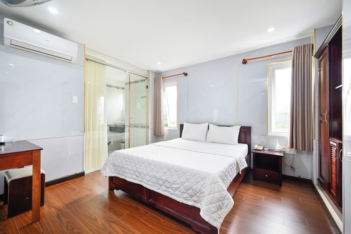 Une chambre avec un grand lit, une table de chevet, un bureau et un appareil de climatisation.