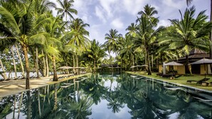 A pool surrounded by palm trees, lounge chairs, and umbrellas. - Peninsula Beach Resort (Ko Chang)