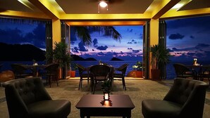 A room with a view of a sunset over water, featuring a table and chairs, and potted plants. - Peninsula Beach Resort (Ko Chang)