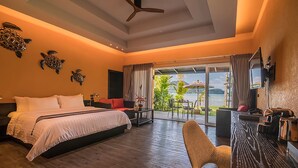 A hotel room with a bed, a desk, a chair, a TV, and a balcony with a view of the sea. - Peninsula Beach Resort (Ko Chang)
