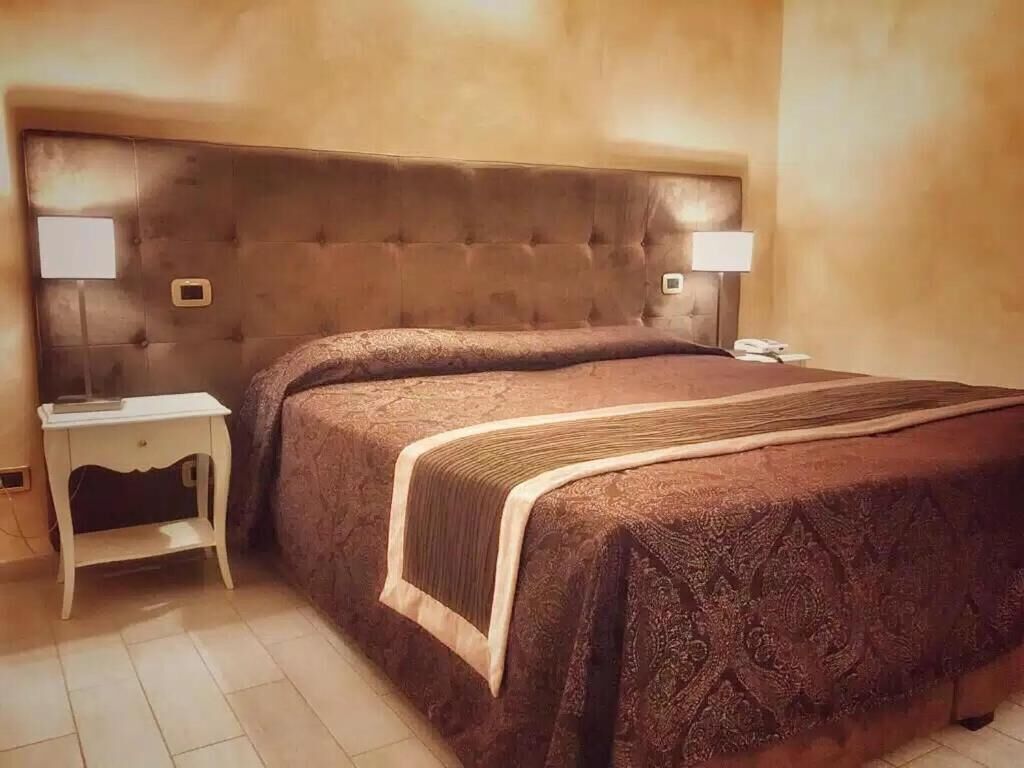 A hotel room with a large bed, two bedside tables, and a headboard.