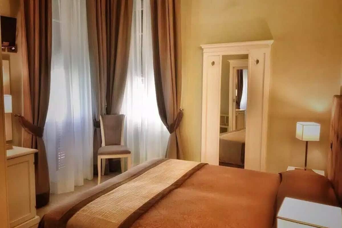 Une chambre d’hôtel avec un lit, une chaise, une armoire et une table de chevet.