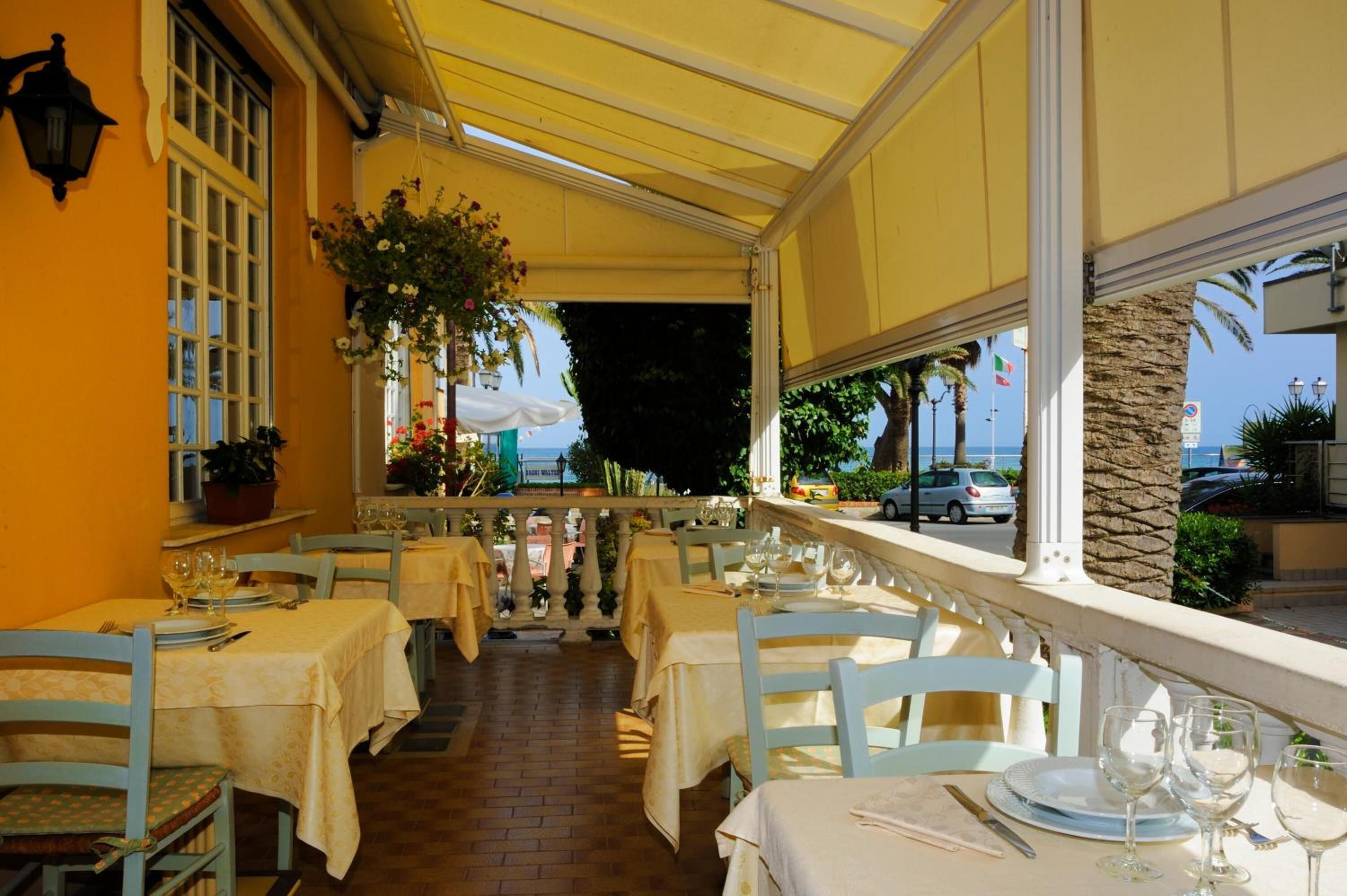 Un restaurant amb terrassa, taules grogues i vista al mar.