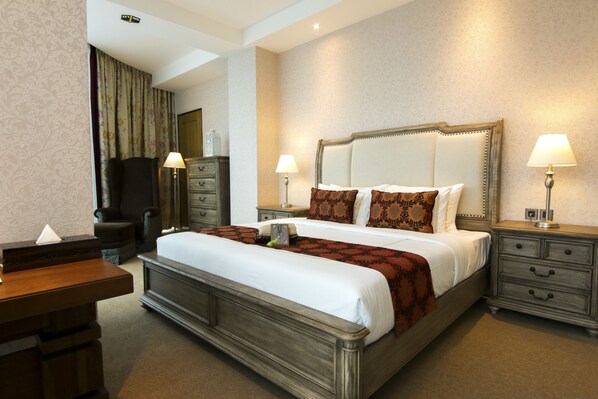 A hotel room with a large bed, two bedside tables with lamps, a dresser, and a desk. - Cinnamon Hotel Boutique Syariah (Bandung)