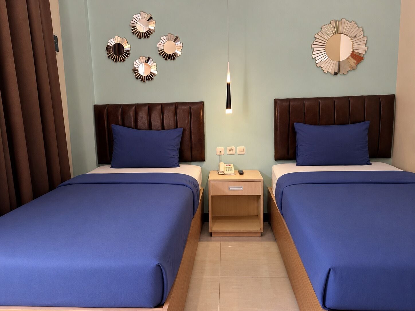 A hotel room with two beds, a nightstand with a phone, and wall decor.