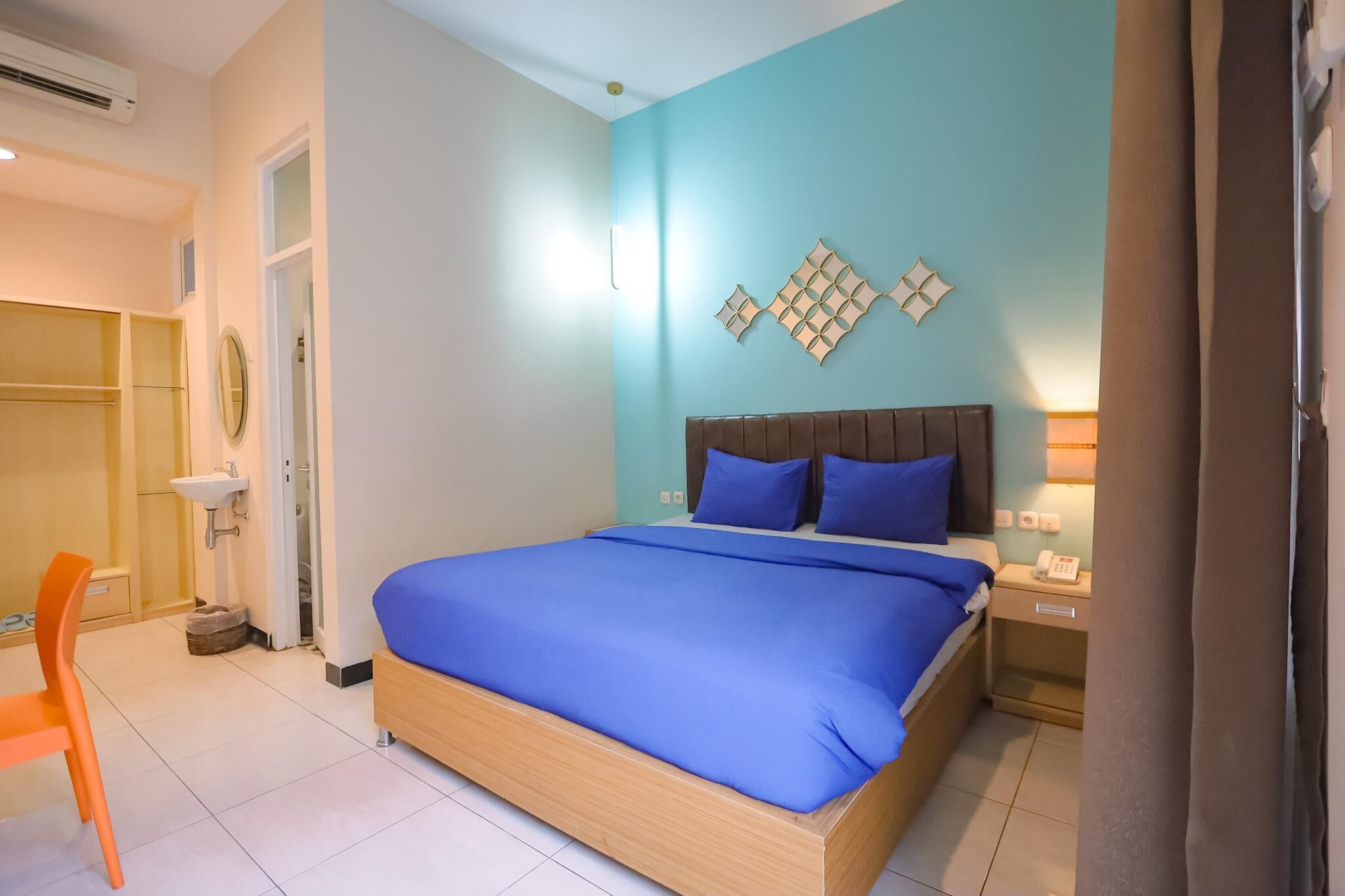 A bedroom with a bed, bedside table, and a nightstand with a phone.