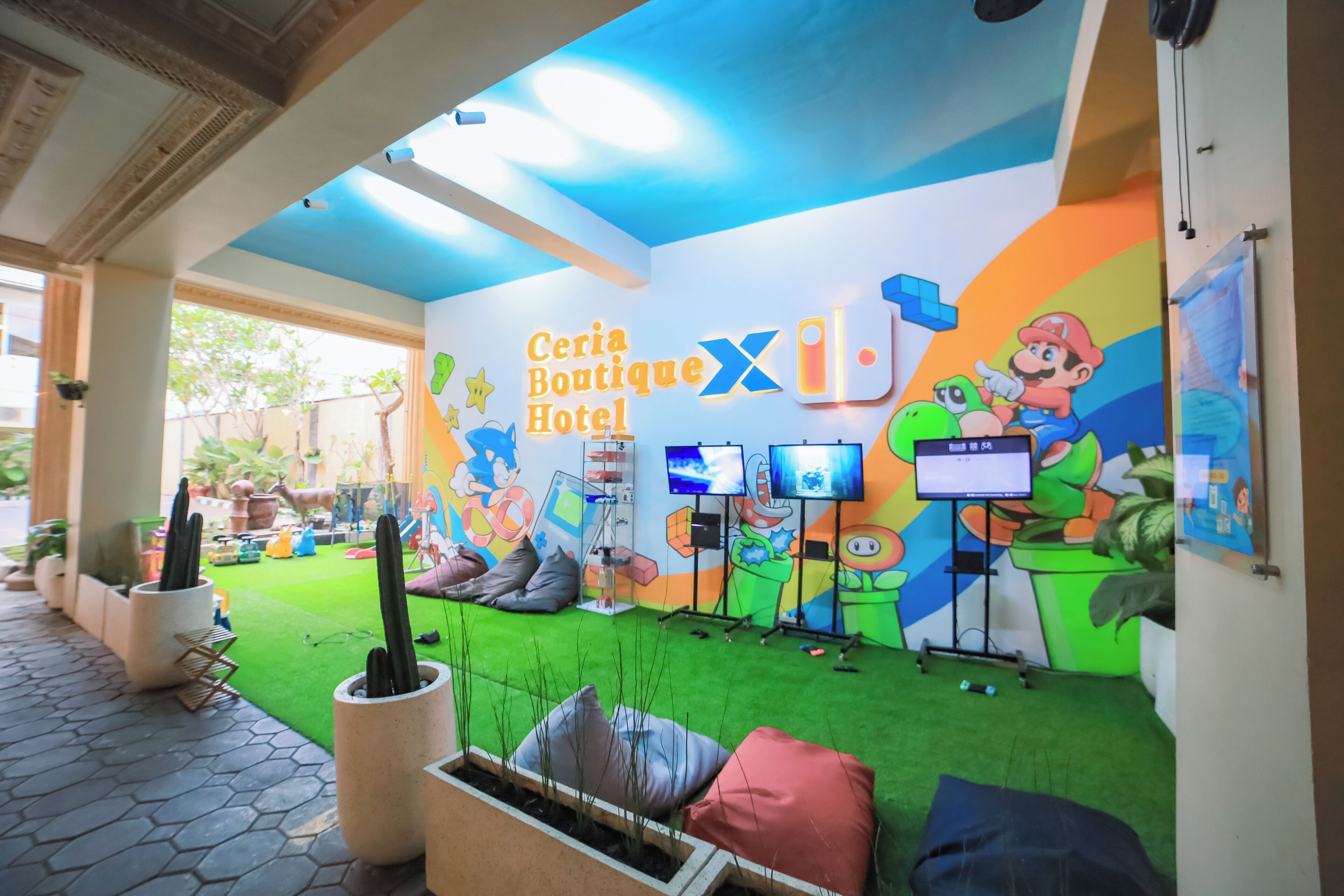 Een hotel lobby met een kleurrijke muurschildering, een groen tapijt en een receptiebalie.