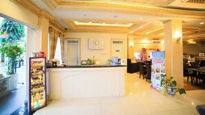 A hotel reception area with a white counter, a chandelier, and a sign for the Game Corner. - Ceria Boutique Hotel (Depok)