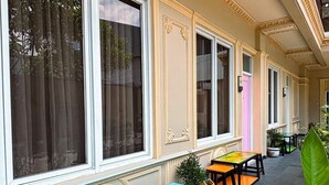 An outdoor seating area with benches and tables, large windows, and decorative moldings. - Ceria Boutique Hotel (Depok)
