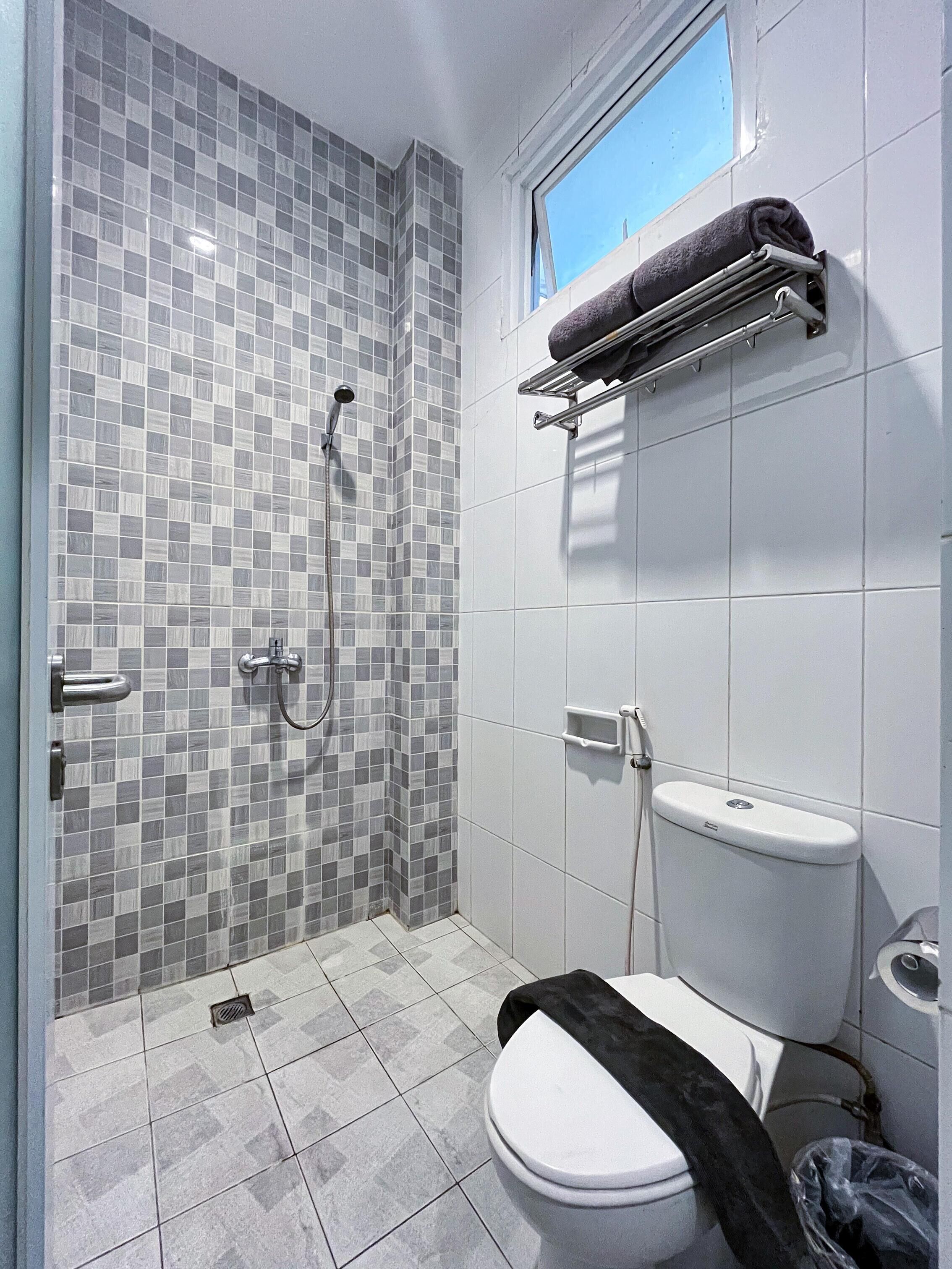 A bathroom with a shower, toilet, and a towel rack.