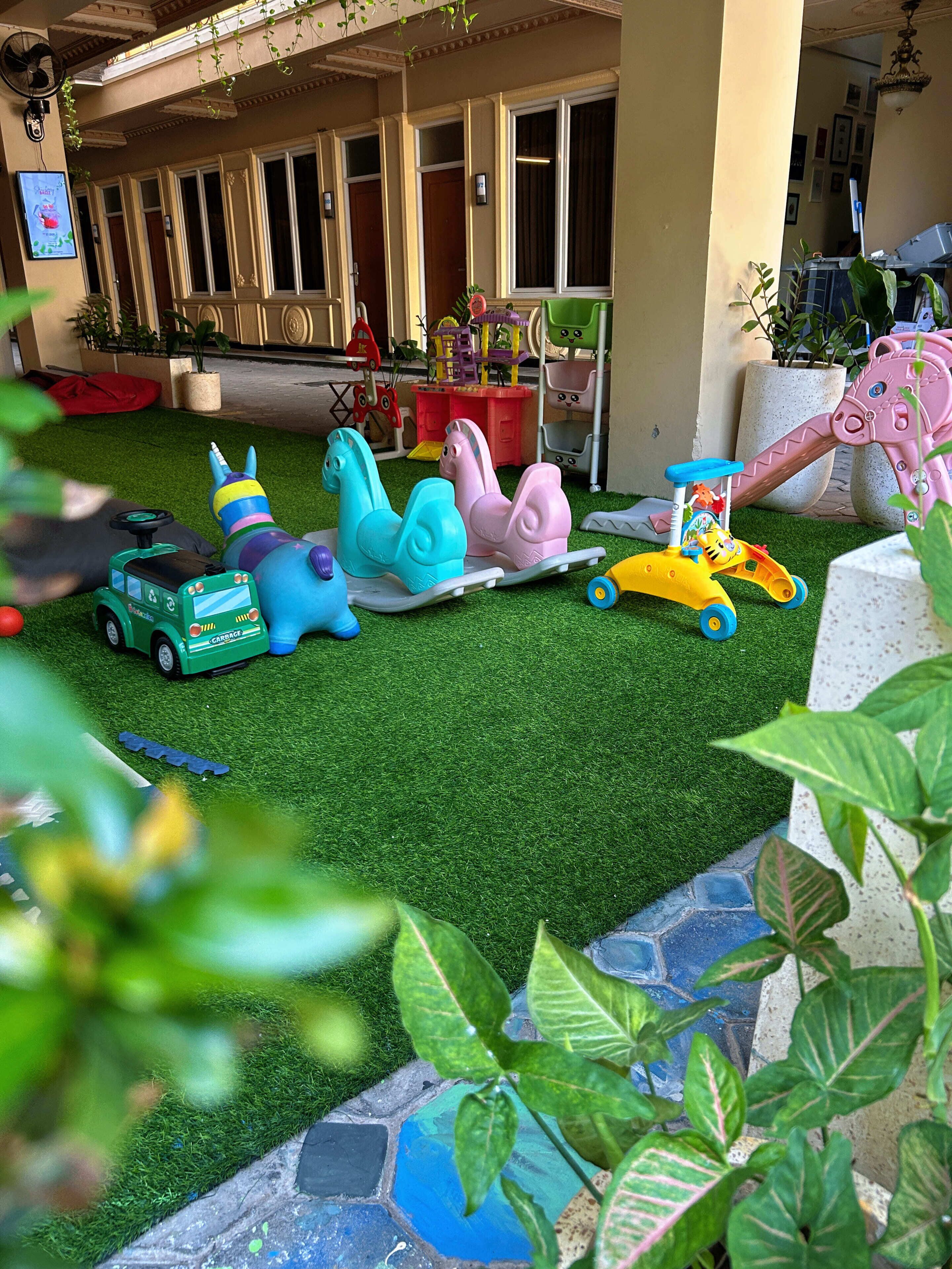 Zona de juegos infantiles con diversos juguetes y un pequeño coche verde.
