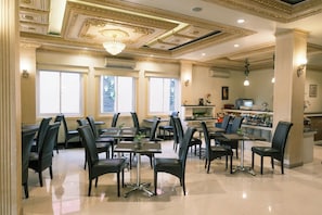 A restaurant with a classic interior, featuring a chandelier, large windows, and a bar area. - Ceria Boutique Hotel (Depok)