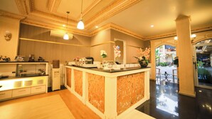 A hotel lobby with a reception desk, decorative ceiling, and a view of the outdoor area. - Ceria Boutique Hotel (Depok)