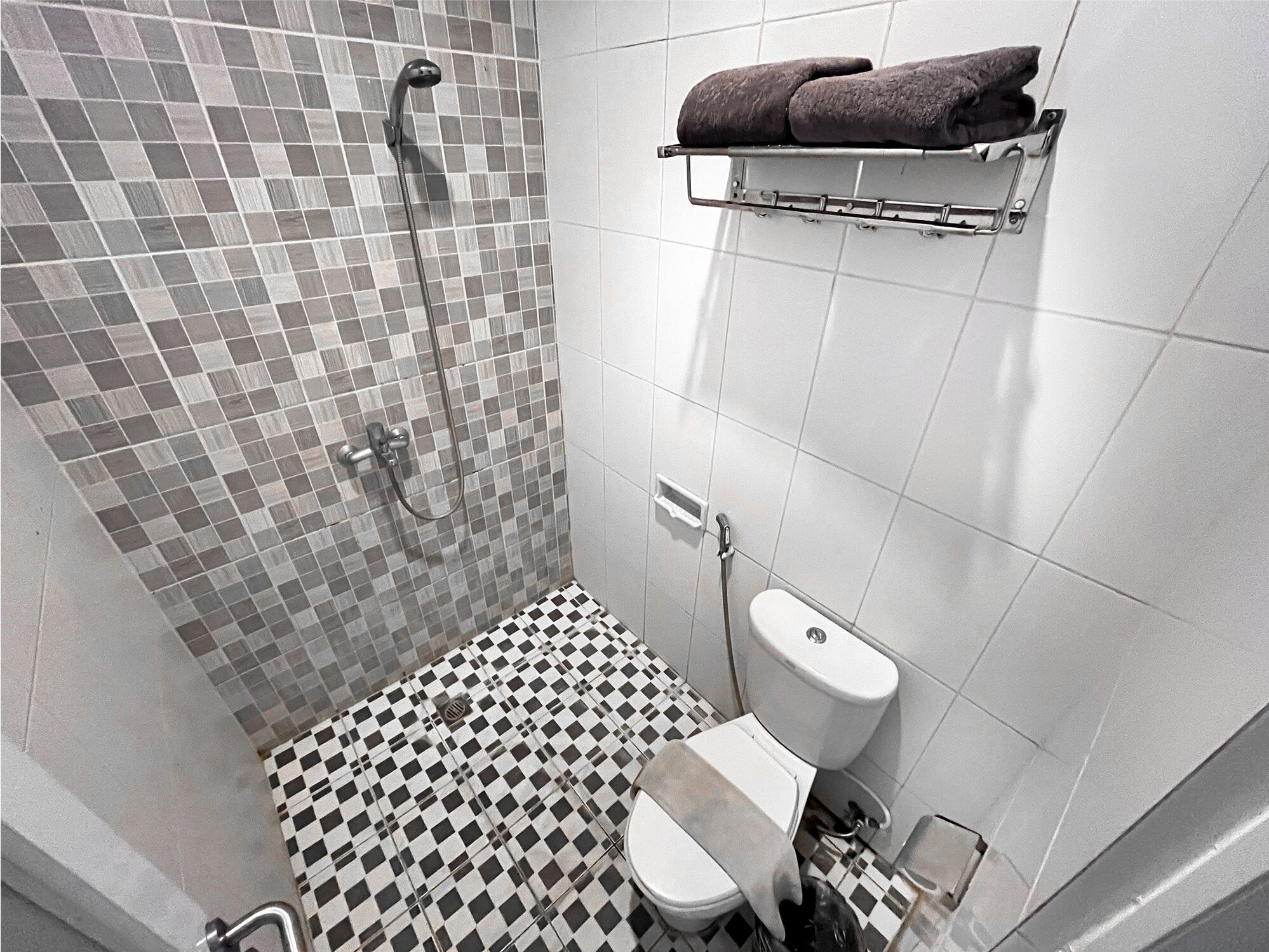 A bathroom with a shower, toilet, and a towel rack.
