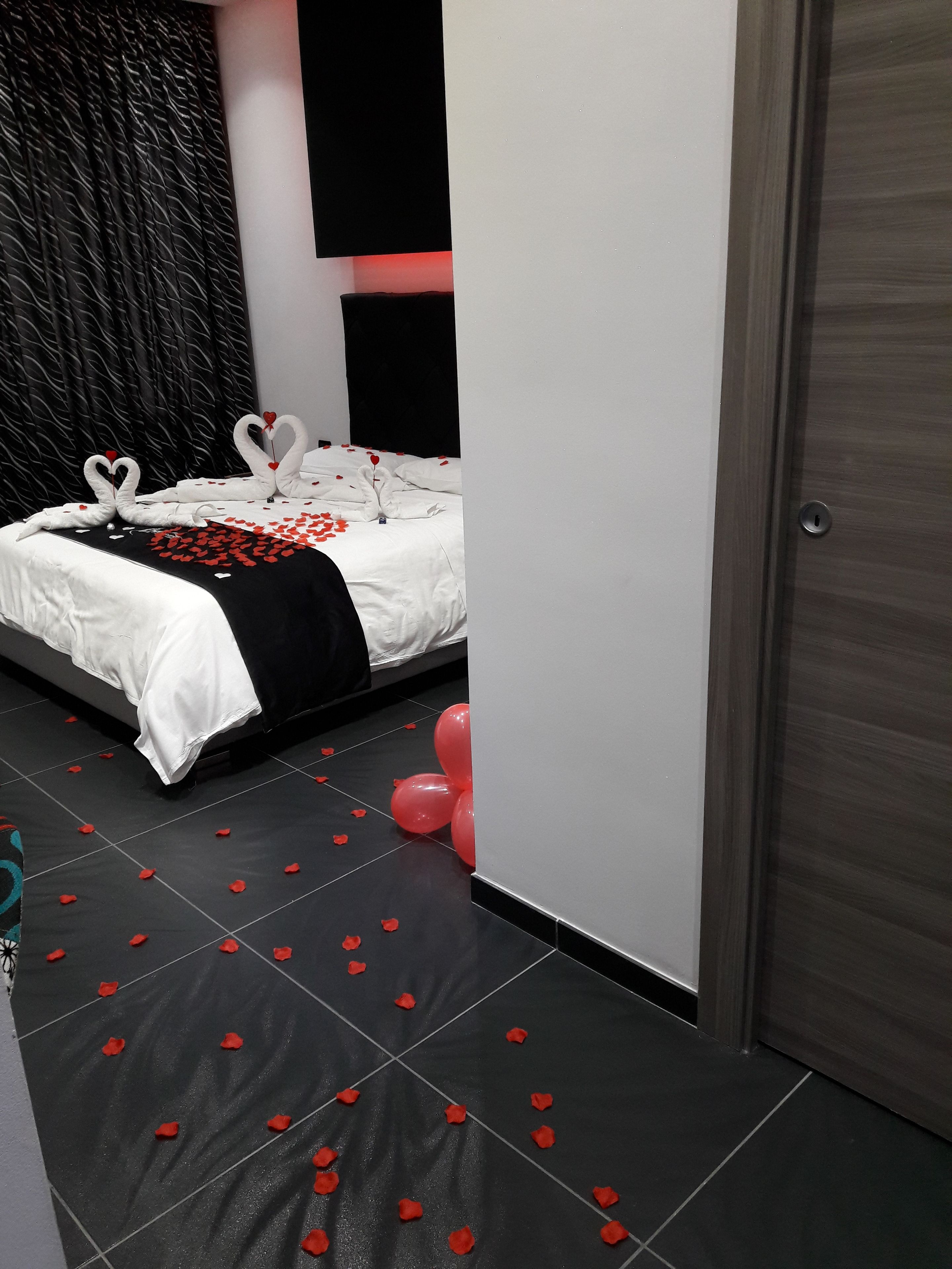 Ett hotellrum med en säng, en svartvit mönstrad sänggavel och en dörr.