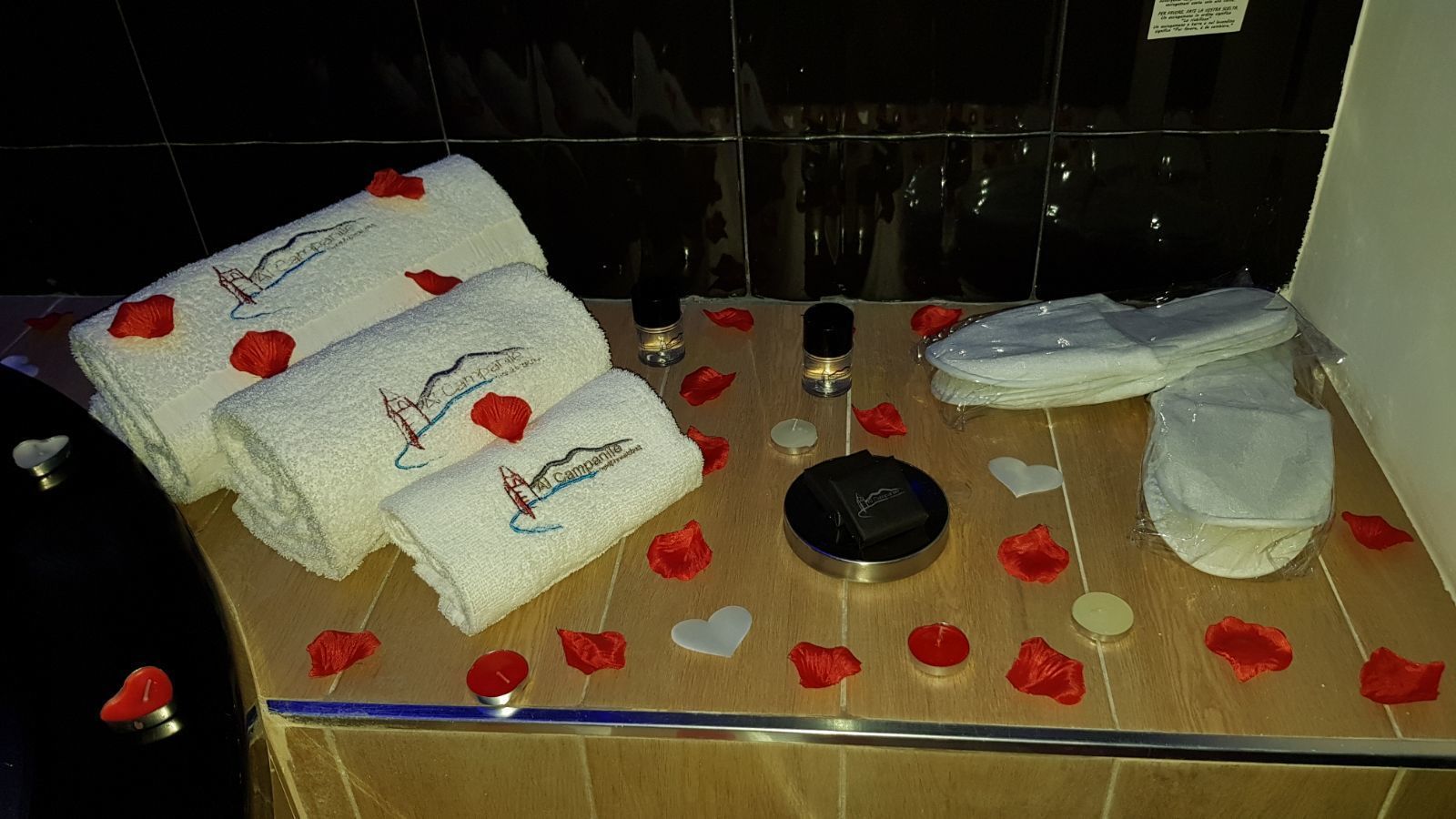 Une salle de bain avec des serviettes, une bouteille et des décorations en forme de cœur.