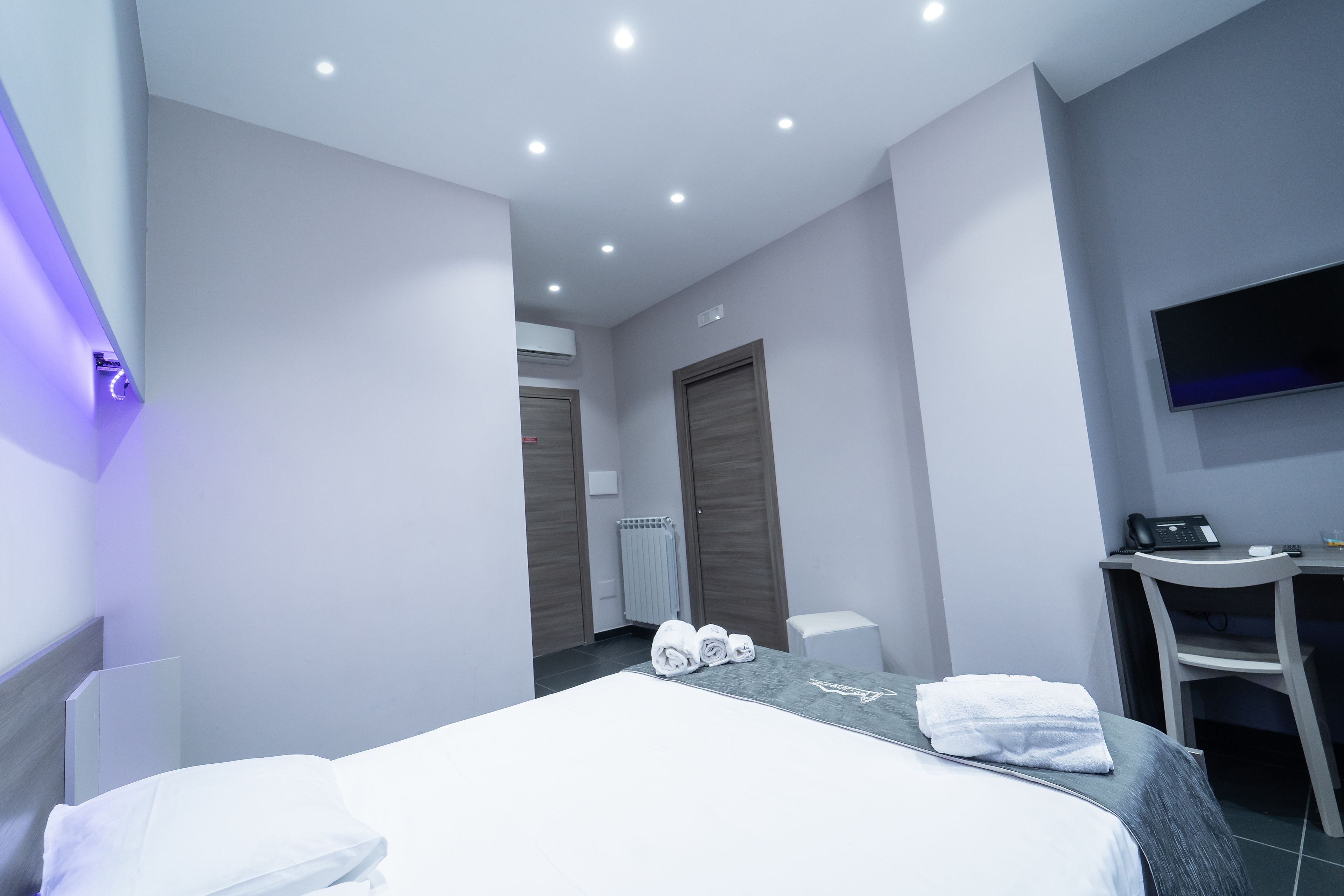 Una habitación de hotel moderna con una cama, un escritorio y un televisor.