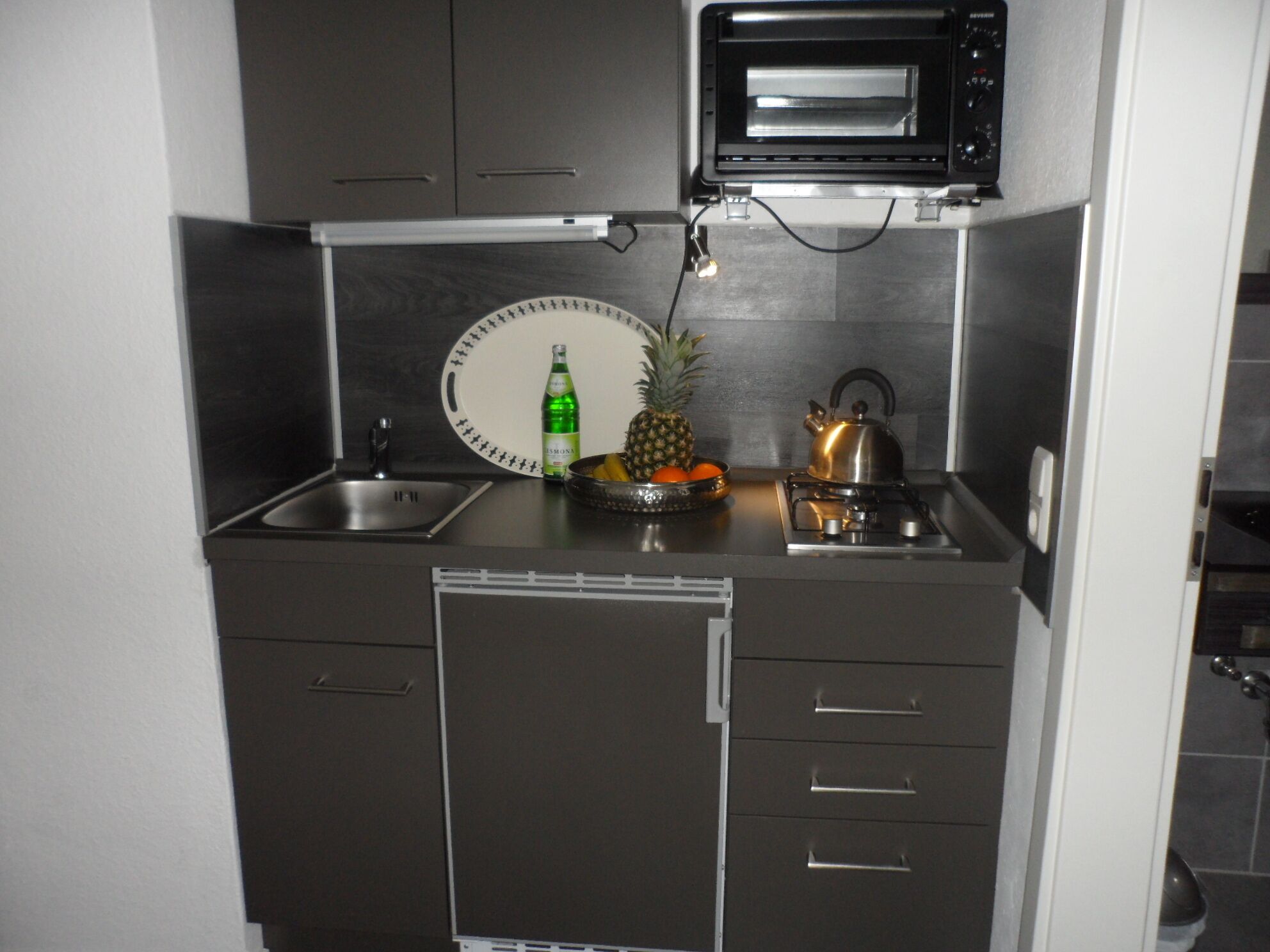 A compact kitchen with a microwave, sink, and stove.