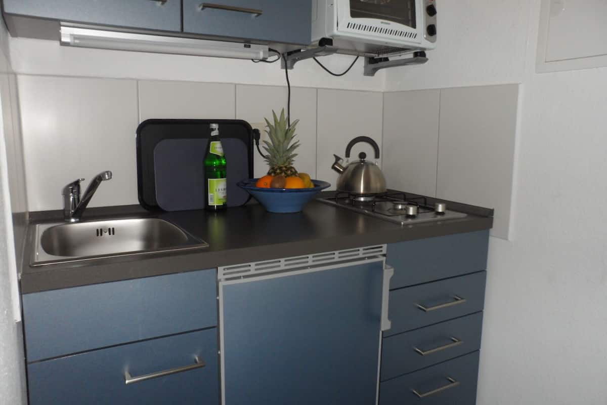 A compact kitchen with a microwave, sink, and a small stove.