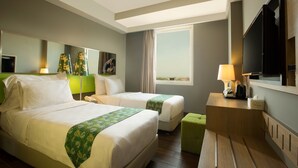 Habitación de hotel con dos camas, un escritorio, un televisor y una ventana con cortinas.