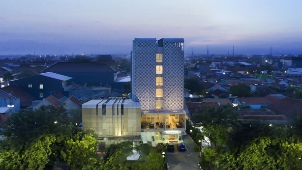 Un hotel moderno con fachada geométrica, varios pisos y una entrada destacada.