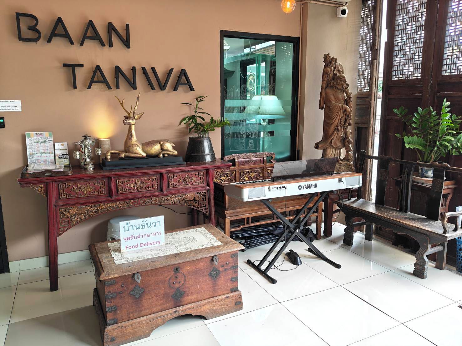 A room with a wooden desk, a Yamaha keyboard, and a statue.