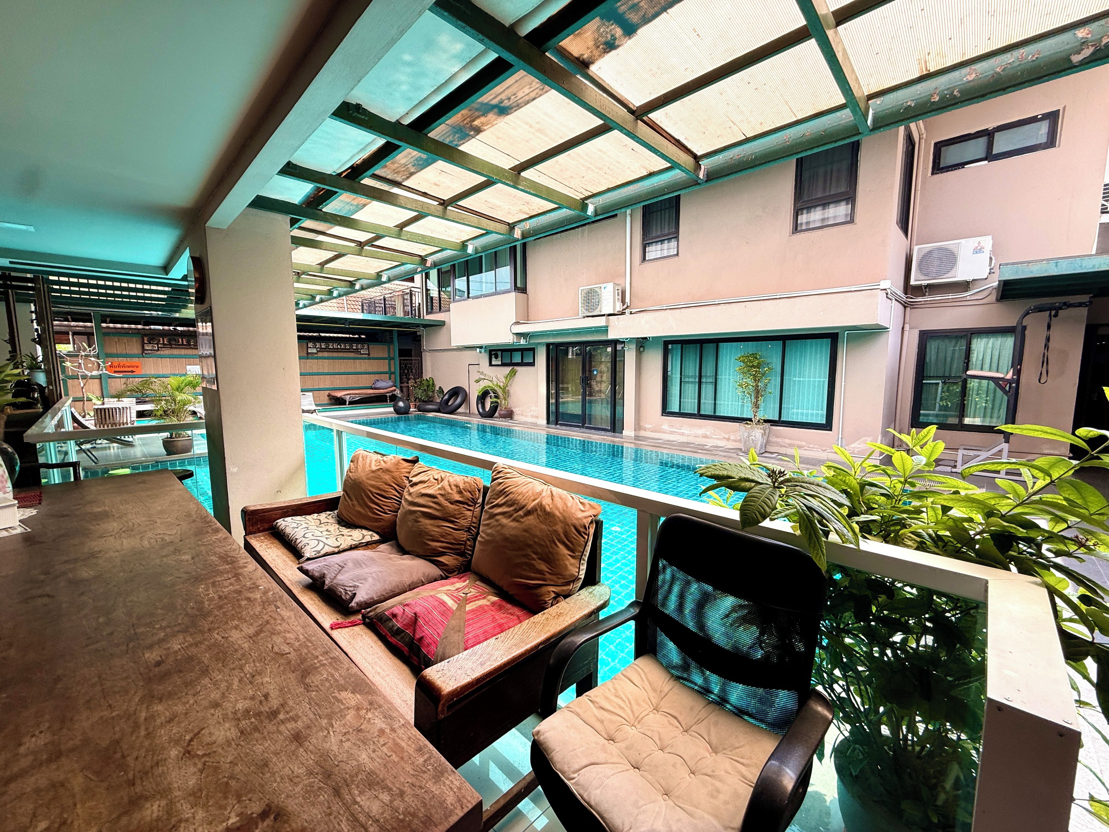 A poolside seating area with a view of a swimming pool and adjacent buildings.