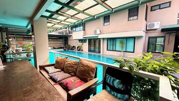 A poolside seating area with a view of a swimming pool and adjacent buildings.