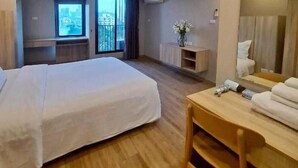 Una habitación de hotel con una cama grande, un escritorio, una silla, un espejo, una ventana con vistas y un equipo de aire acondicionado.