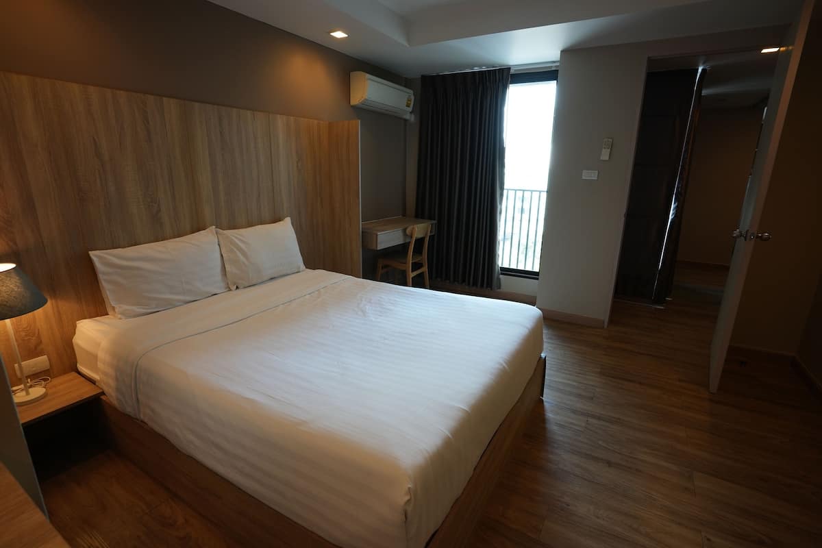 A hotel room with a large bed, a desk, and a view of the outdoors.