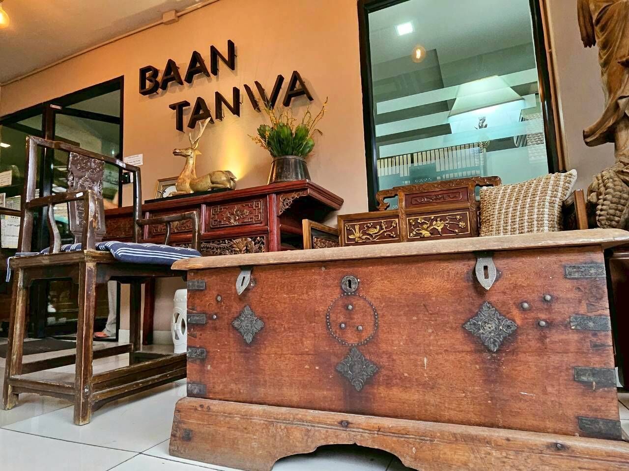A furniture store interior with a wooden display counter, a sign reading "BAAN TANIVA", and various furniture items.
