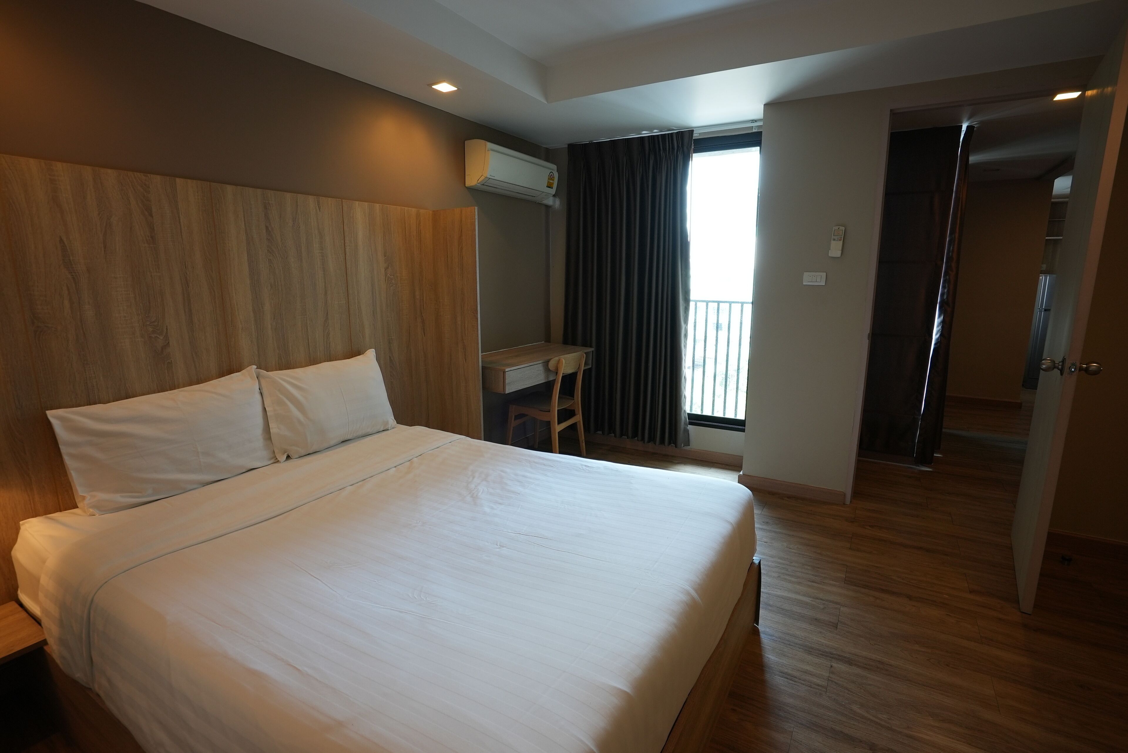 A hotel room with a large bed, a desk, and a view of the outside.