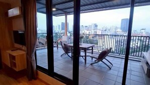 Una habitación con ventanas amplias, un balcón con mobiliario exterior y suelo de madera.