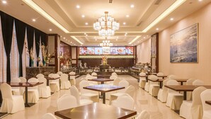A spacious restaurant with multiple tables and chairs, a bar area, and a chandelier. - Hangzhou OUYAMEI International Hotel (Hangzhou)