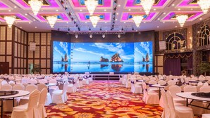 A banquet hall with a large screen displaying a scenic view, white chairs, and chandeliers. - Hangzhou OUYAMEI International Hotel (Hangzhou)