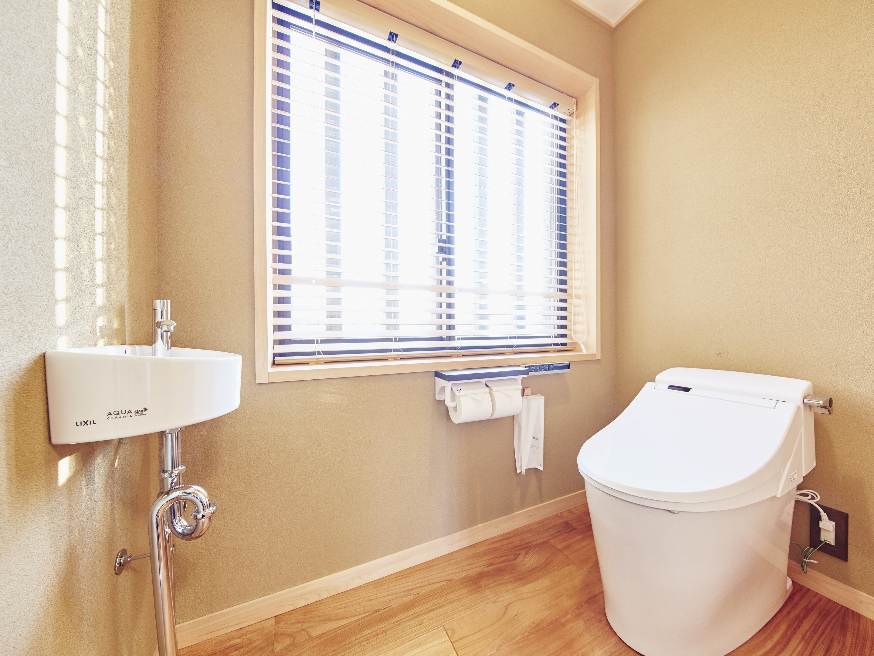 A bathroom with a white sink, toilet, and window with blinds.