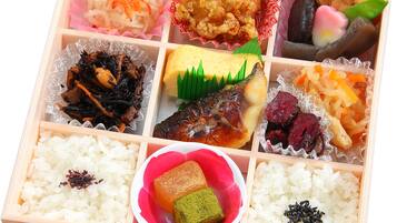A wooden box containing various food items, including rice, fish, and vegetables.