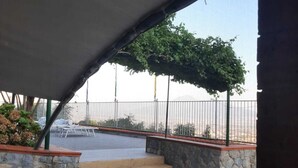 Ett takförsett utomhusområde med stentrappor som leder till en sittplats under en pergola.