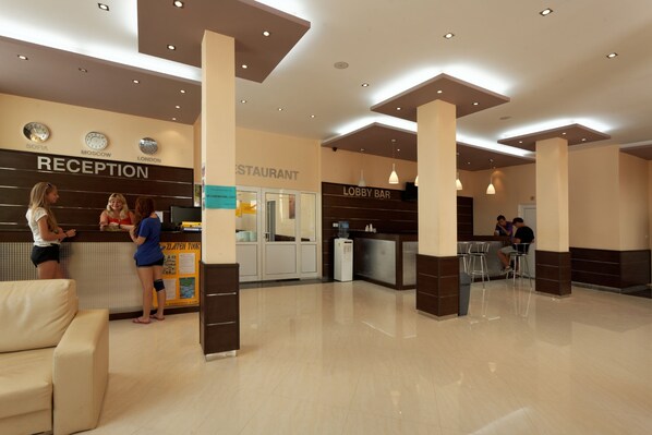 A hotel reception area with a reception desk, a lobby bar, and a restaurant.