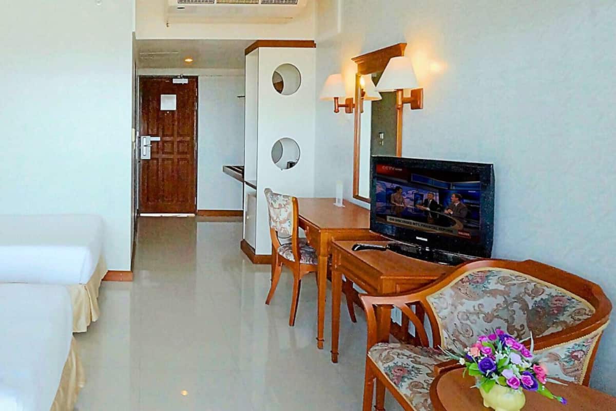Une chambre d’hôtel avec deux lits, une télévision, un bureau et une chaise.