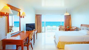 Quarto de hotel com cama, escrivaninha, televisão e varanda com vista para o mar.