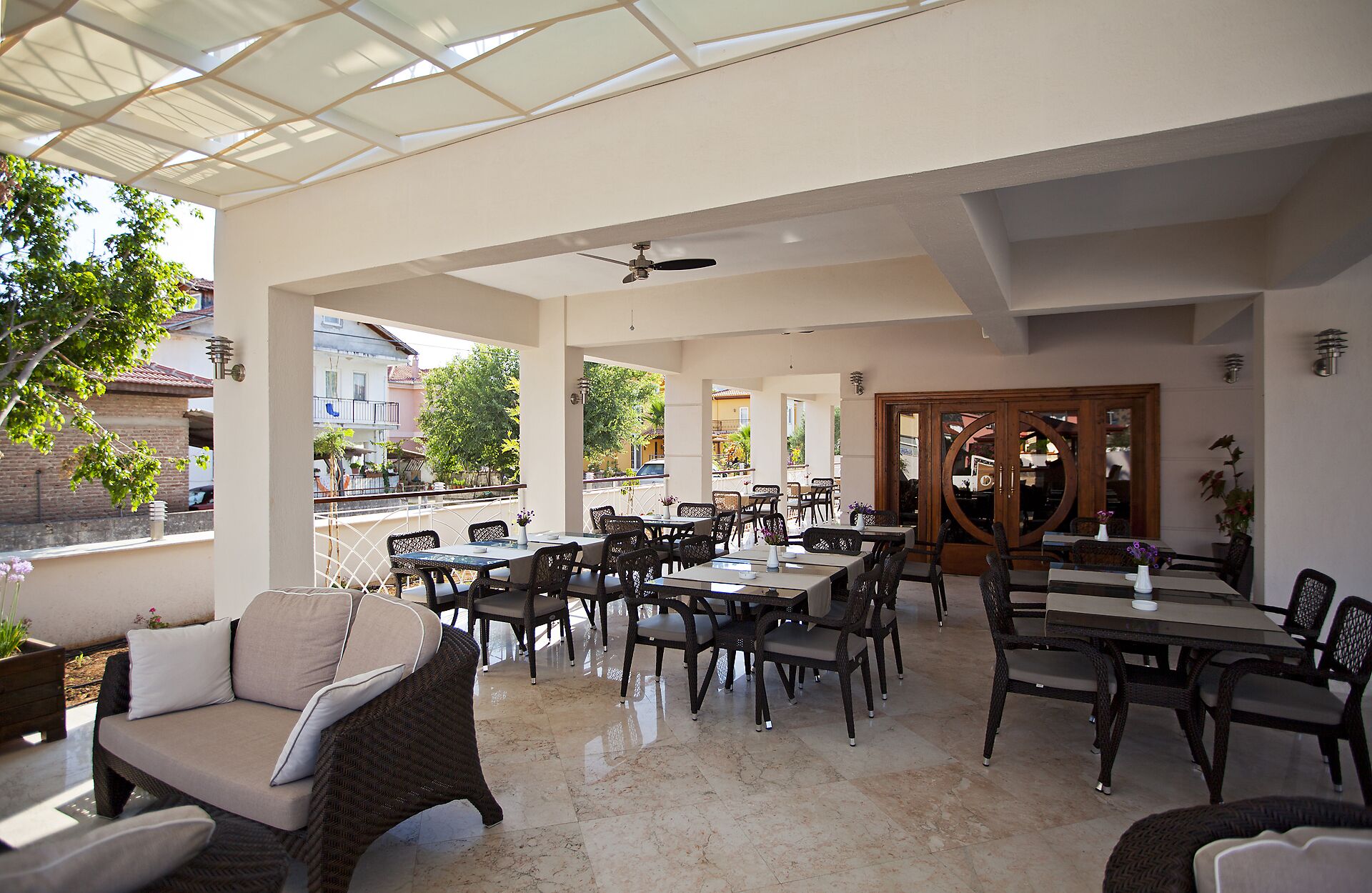 An outdoor cafe with tables and chairs, a glass ceiling, and a view of the street.