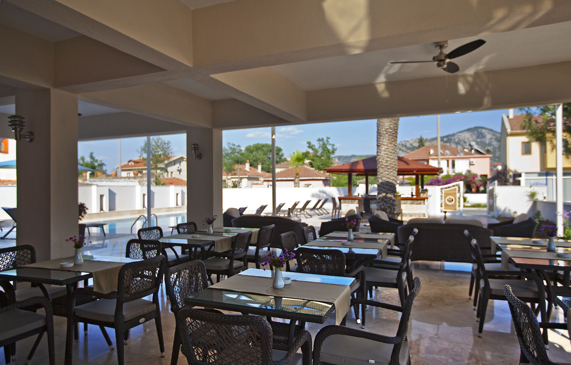 A restaurant with outdoor seating, large windows, and a view of the surrounding area.