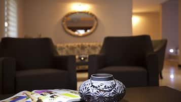 Una sala moderna con dos sillones oscuros, un florero decorativo y una revista sobre una mesa de madera.