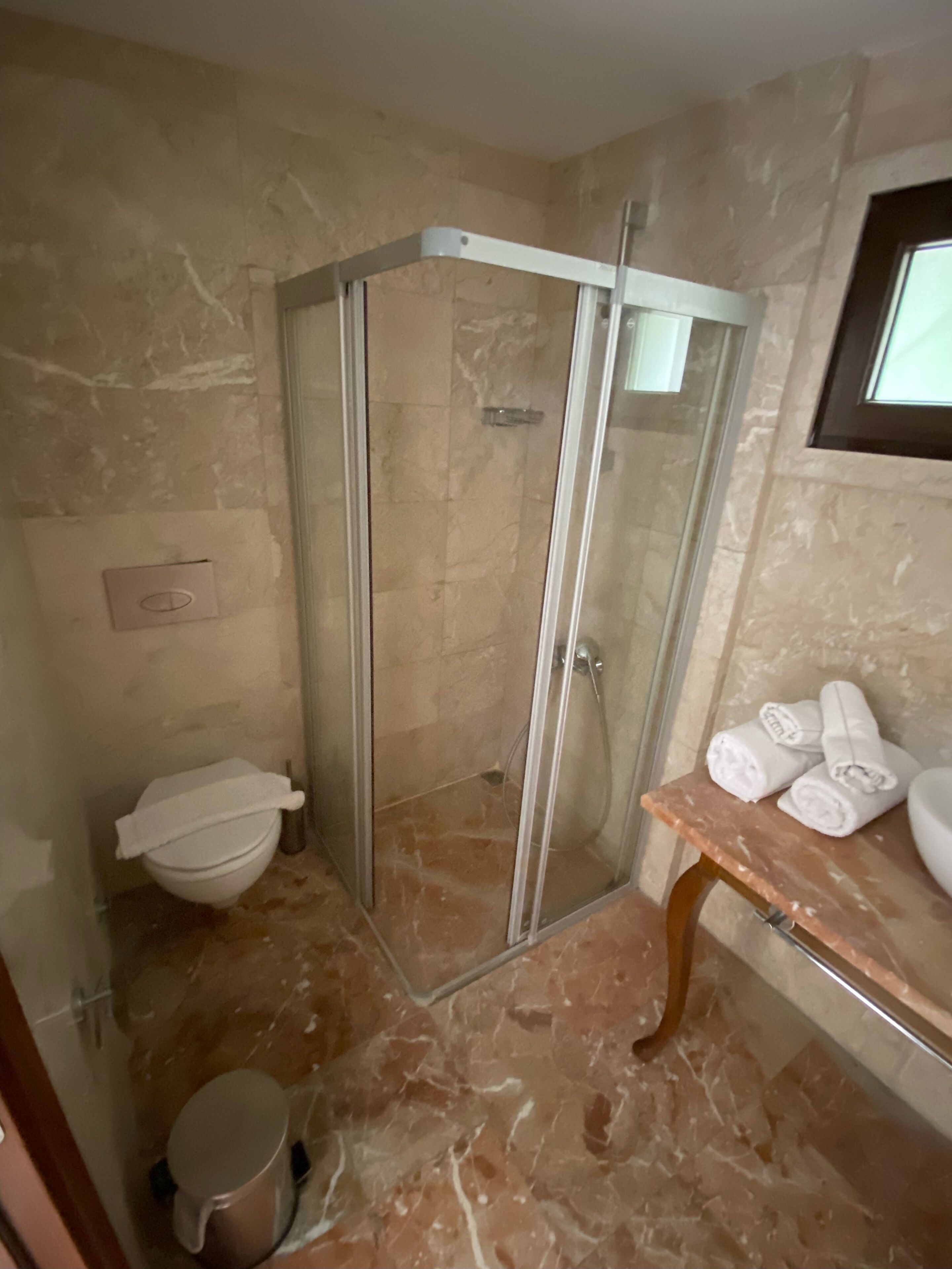 Une salle de bain avec une douche à parois de verre, des toilettes et un lavabo avec des serviettes.