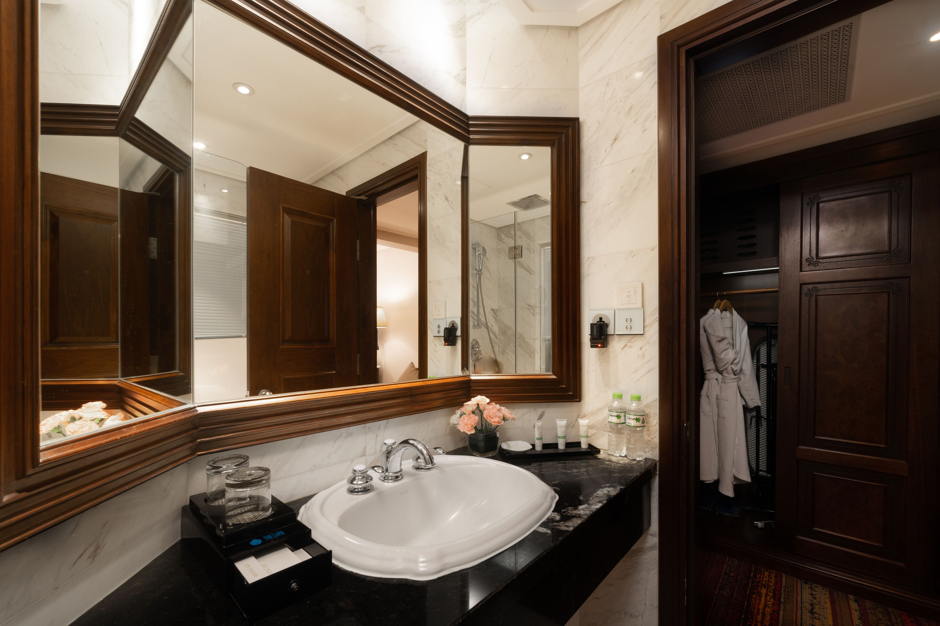 A bathroom with a large mirror, a sink, and a shower.