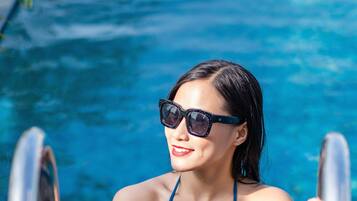 A person in a blue bikini standing in a pool with metal railings.