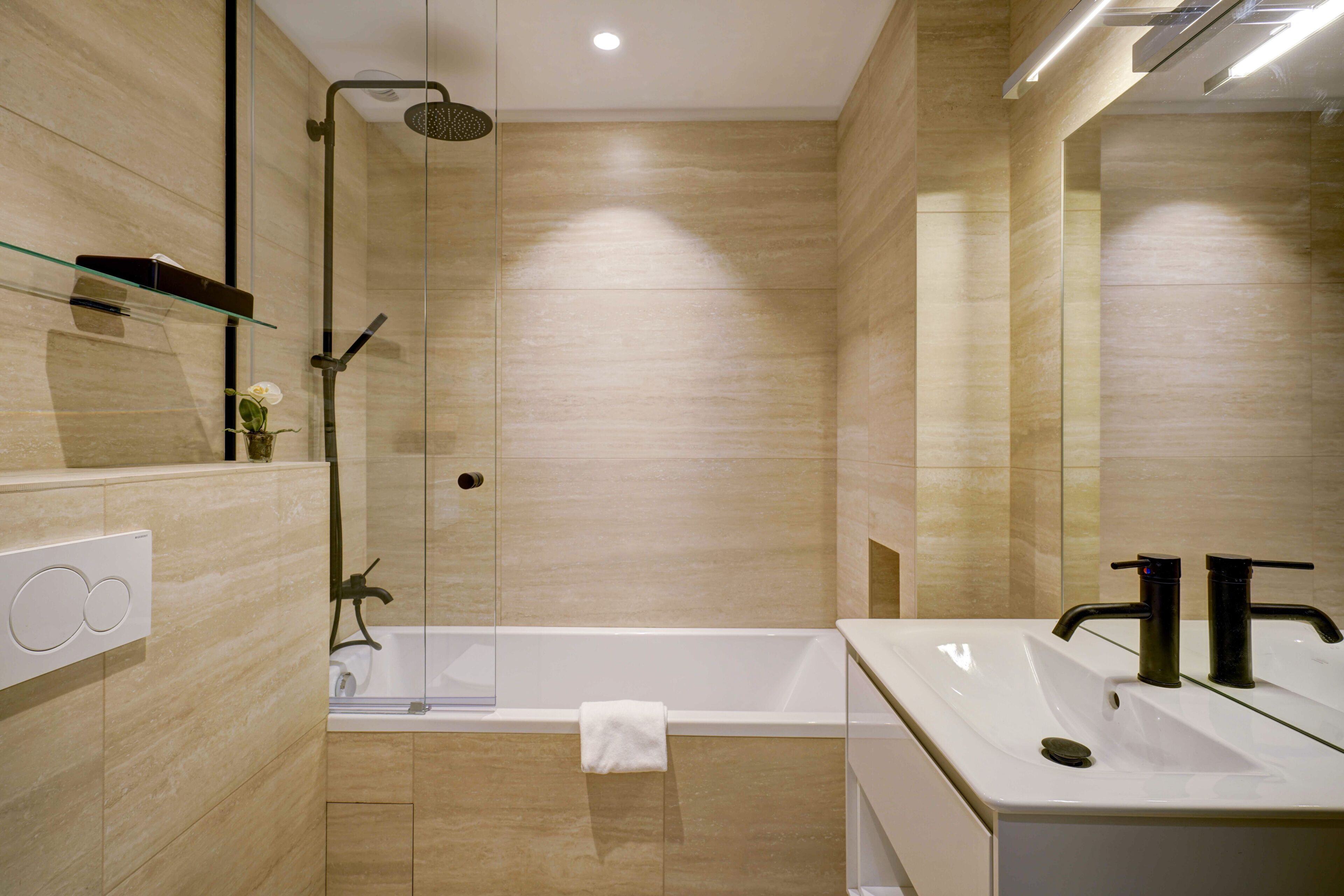 A modern bathroom with a glass-enclosed shower, a white bathtub, and a large mirror.