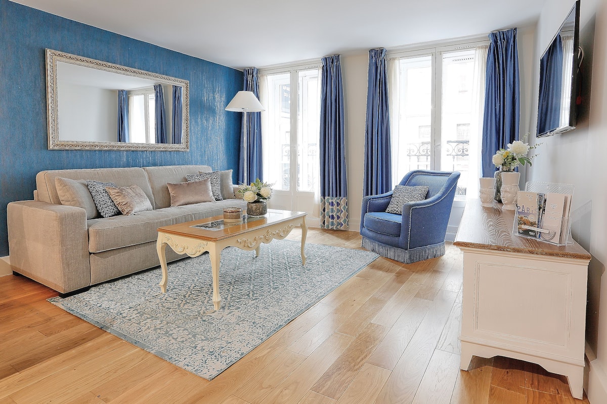 A living room with a sofa, armchair, coffee table, and a side table with a vase.