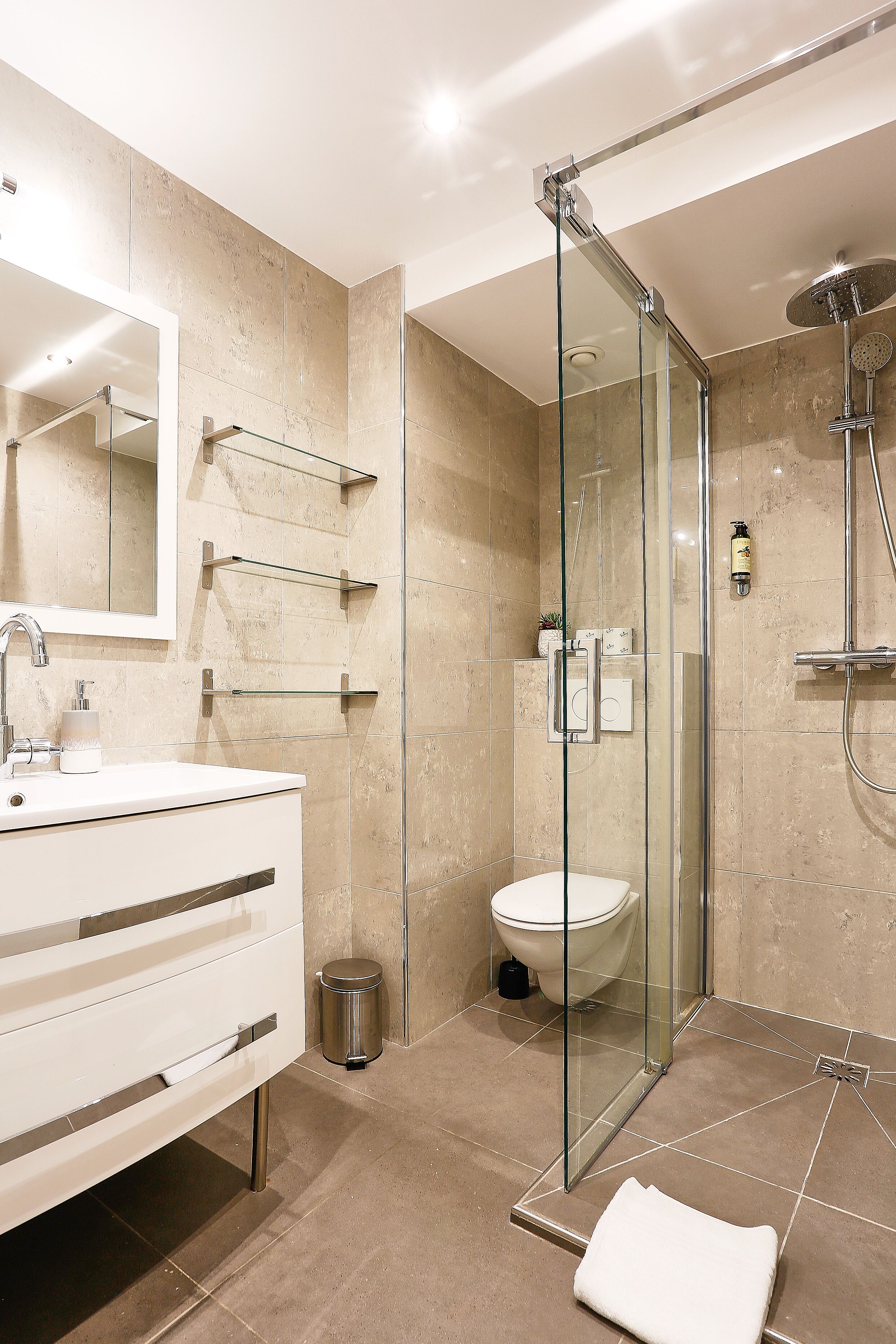 A modern bathroom with a glass-enclosed shower, a white sink, and a toilet.